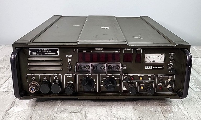Black Military style unit with S-Meter on right, speaker on left, 8 knobs and 8 nixie tubes for frequency indication. 